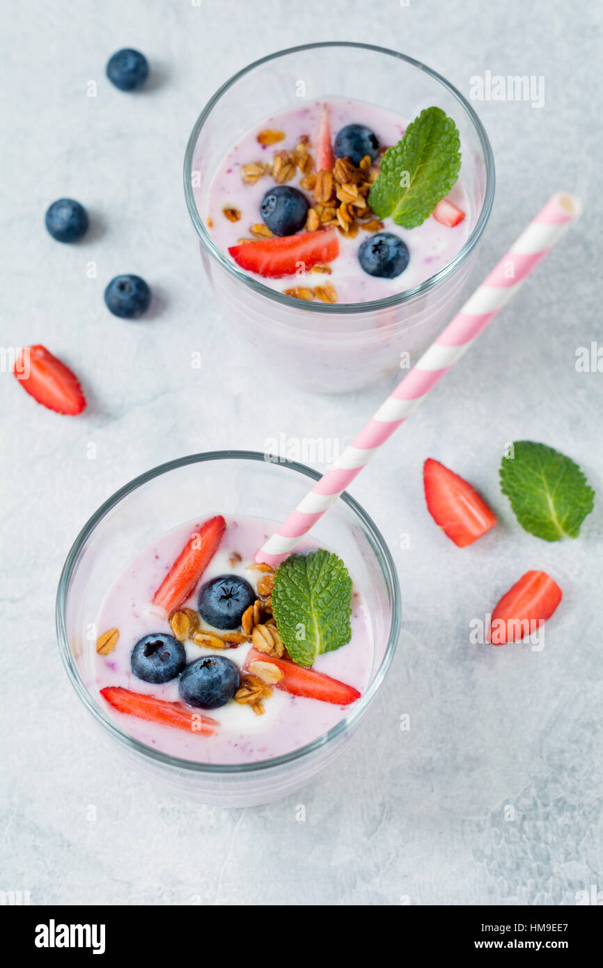 Gesunde Heidelbeeren und Erdbeeren Smoothies, garniert mit frischen Beeren Müsli und Minze Blatt mit cocktail-Rohr Stockfoto