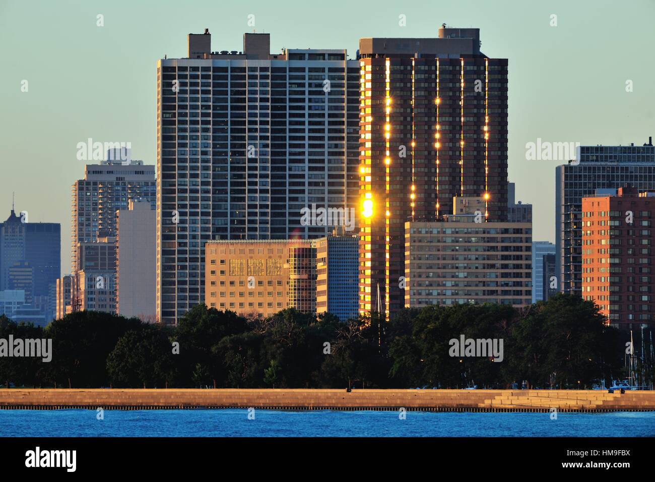 Die Sonne spiegelt sich auf Fenster und Balkone auf einem hohen Kondominium mit Blick auf den Chicago Montrose Hafen und den Lake Michigan. Chicago, Illinois, USA. Stockfoto