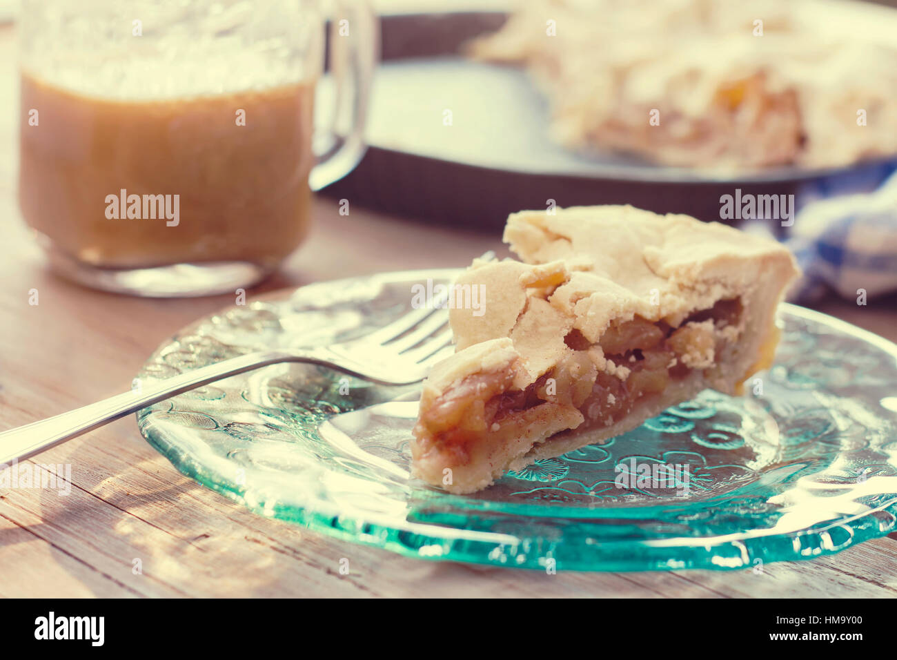 Stück leckeren hausgemachten Apfelkuchen auf eine dekorative Glasplatte mit Tasse Kaffee im Hintergrund Stockfoto