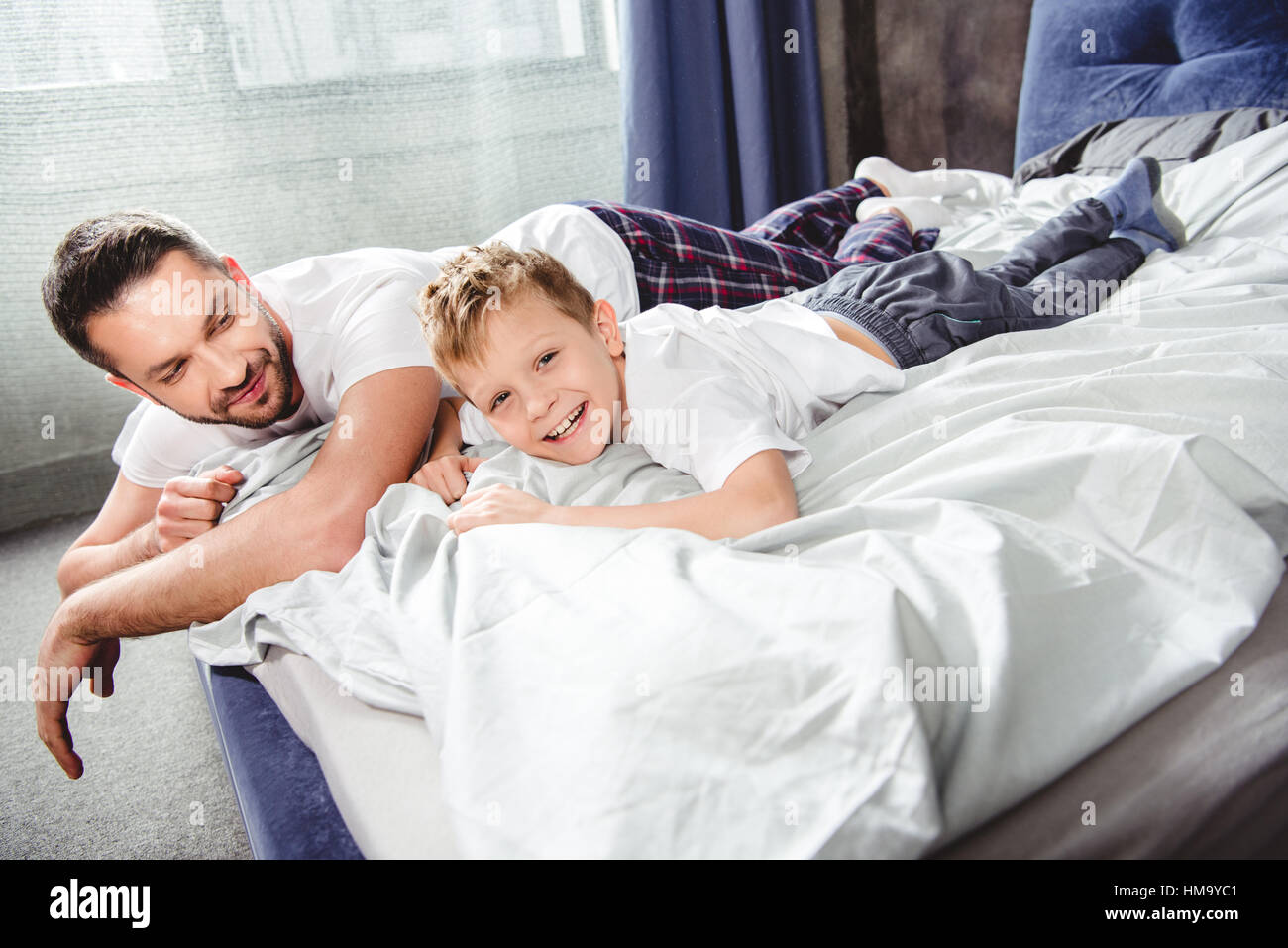 Glücklicher Vater und Sohn im Bett Stockfoto