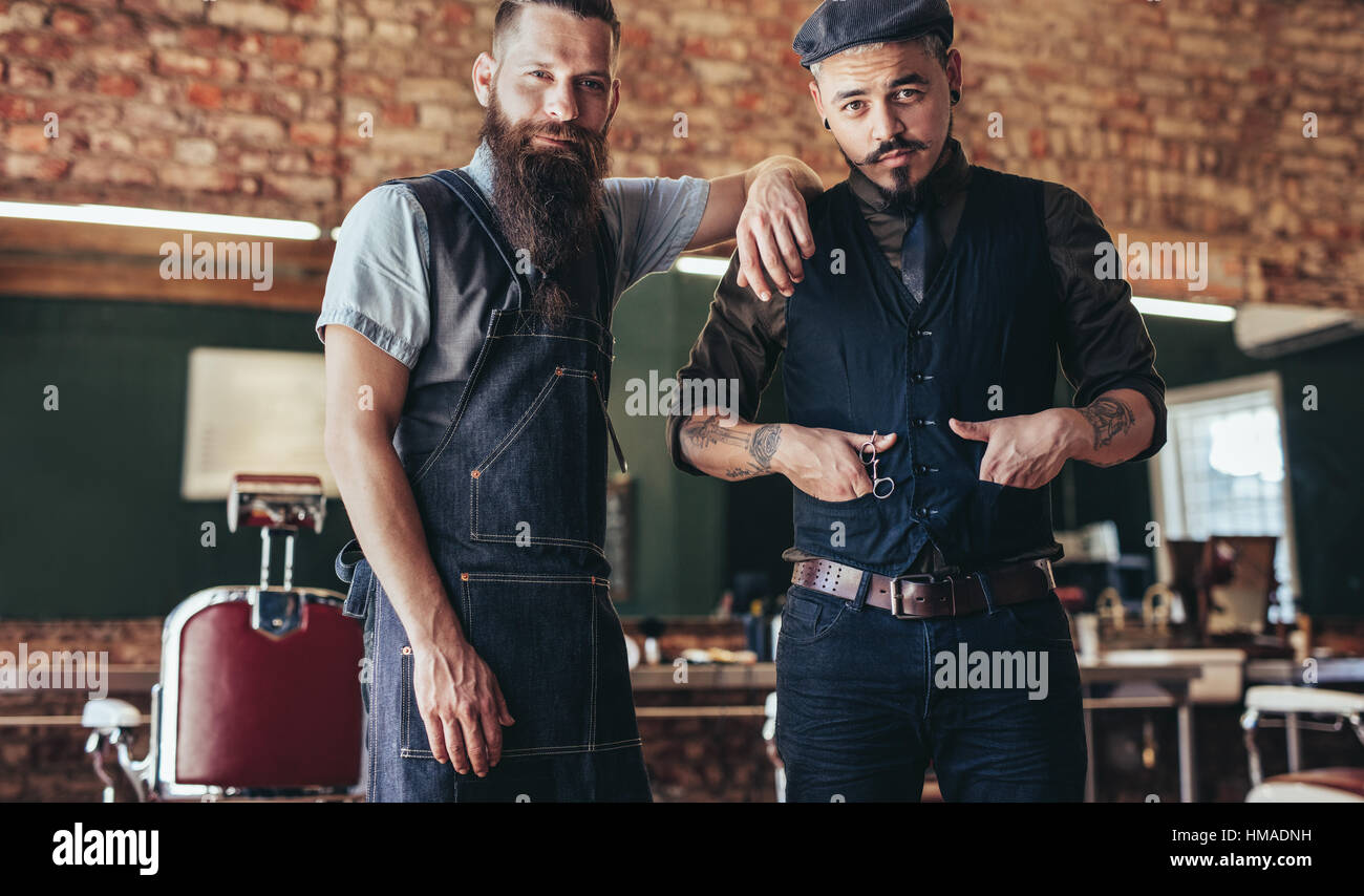 Schuss von Barbier mit stilvollen jungen Mann stehen im Salon. Zwei Männer stehen beim Friseur. Stockfoto