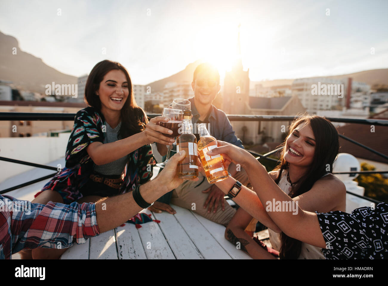 Glückliche junge Leute Toasten Getränke auf einer Party auf dem Dach. Jungen Freunden rumhängen und Getränke zu genießen. Stockfoto