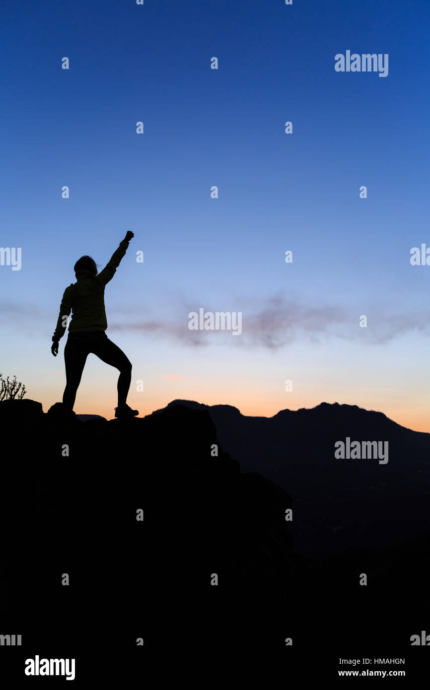 Frau Wandern Silhouette im Sonnenuntergang, Berge und Meer. Weibliche Wanderer, Bergsteiger oder Trailläufer mit Mountain Top betrachten Beauti ausgestreckten Armen Stockfoto