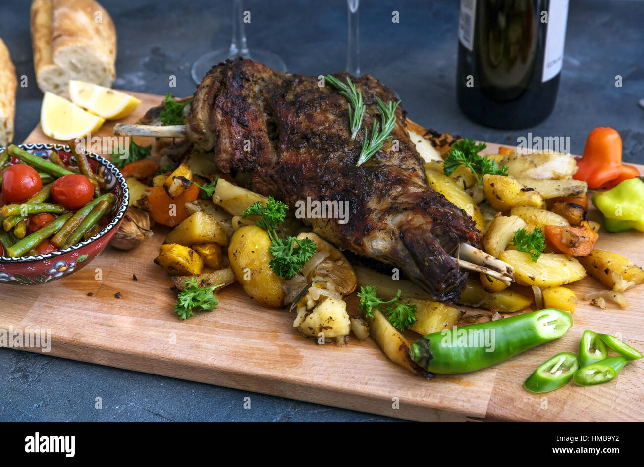 Gebratene Lammschulter mit Bratkartoffeln und Karotten in einem rustikalen Holzbrett, Ansicht von oben gestylt Stockfoto