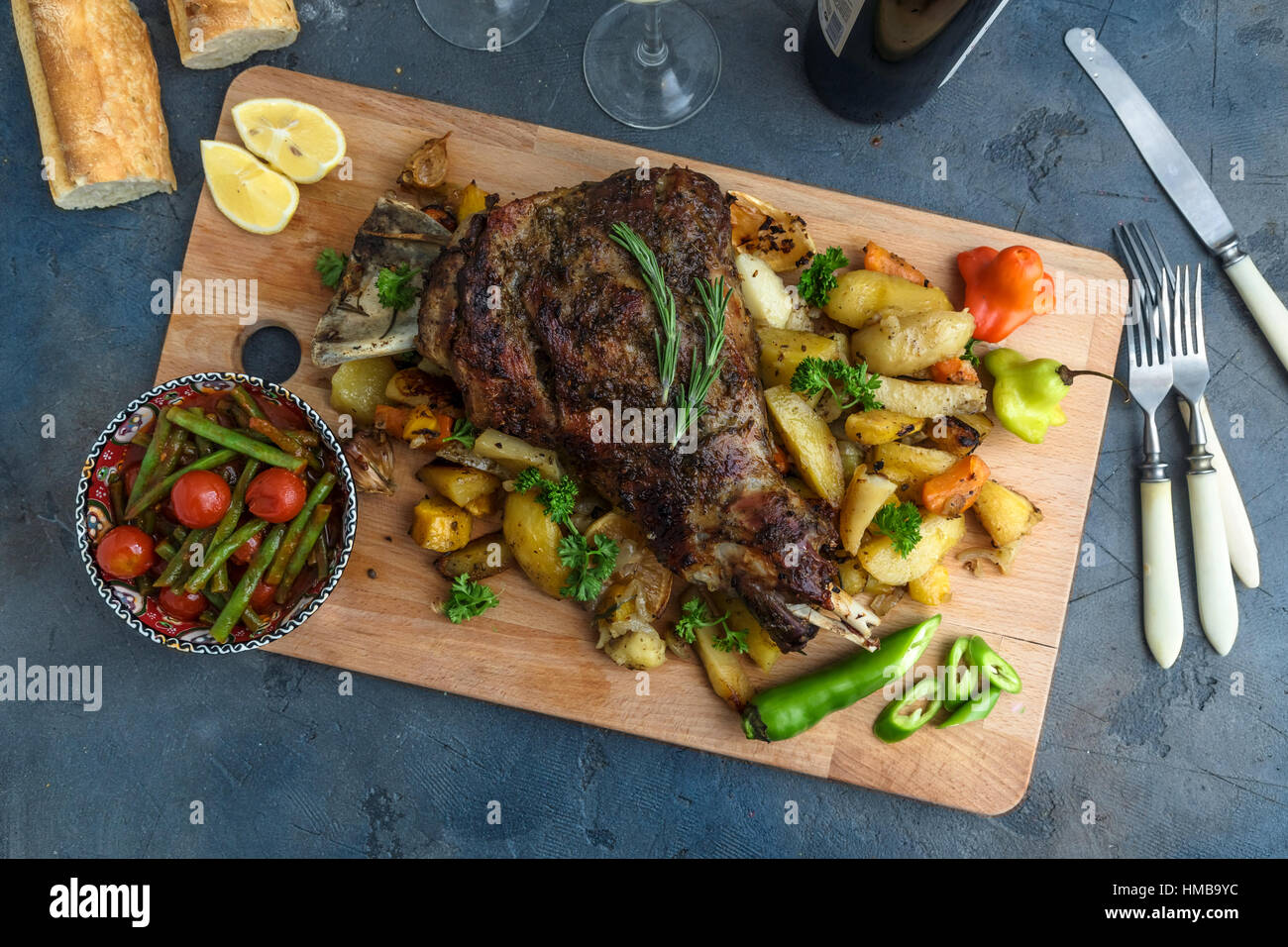 Gebratene Lammschulter mit Bratkartoffeln und Karotten in einem rustikalen Holzbrett, Ansicht von oben gestylt Stockfoto