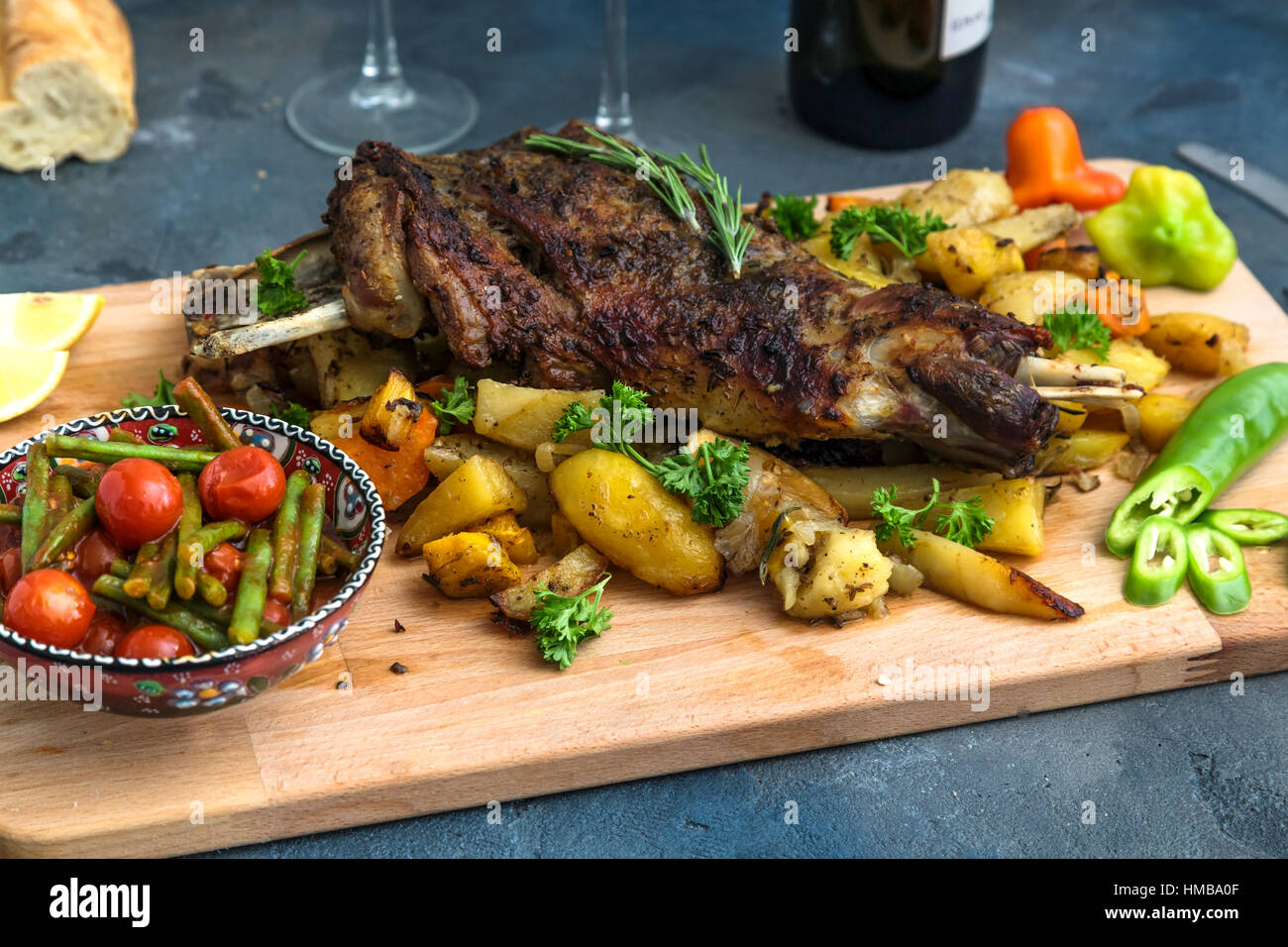 Gebratene Lammschulter mit Bratkartoffeln und Karotten in einem rustikalen Holzbrett, Ansicht von oben gestylt Stockfoto
