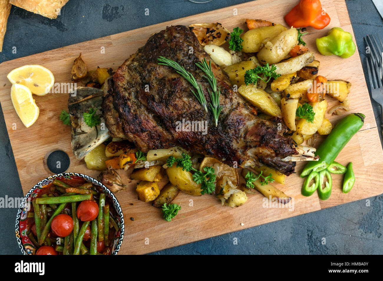 Gebratene Lammschulter auf gebackenen Kartoffeln und Karotten, Holzbrett, Ansicht von oben Stockfoto