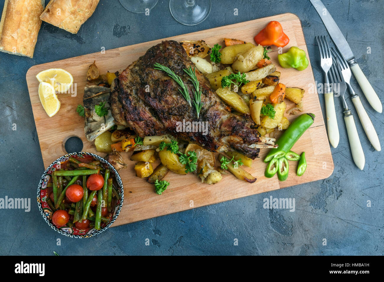Gebratene Lammschulter auf gebackenen Kartoffeln und Karotten, Holzbrett, Ansicht von oben Stockfoto
