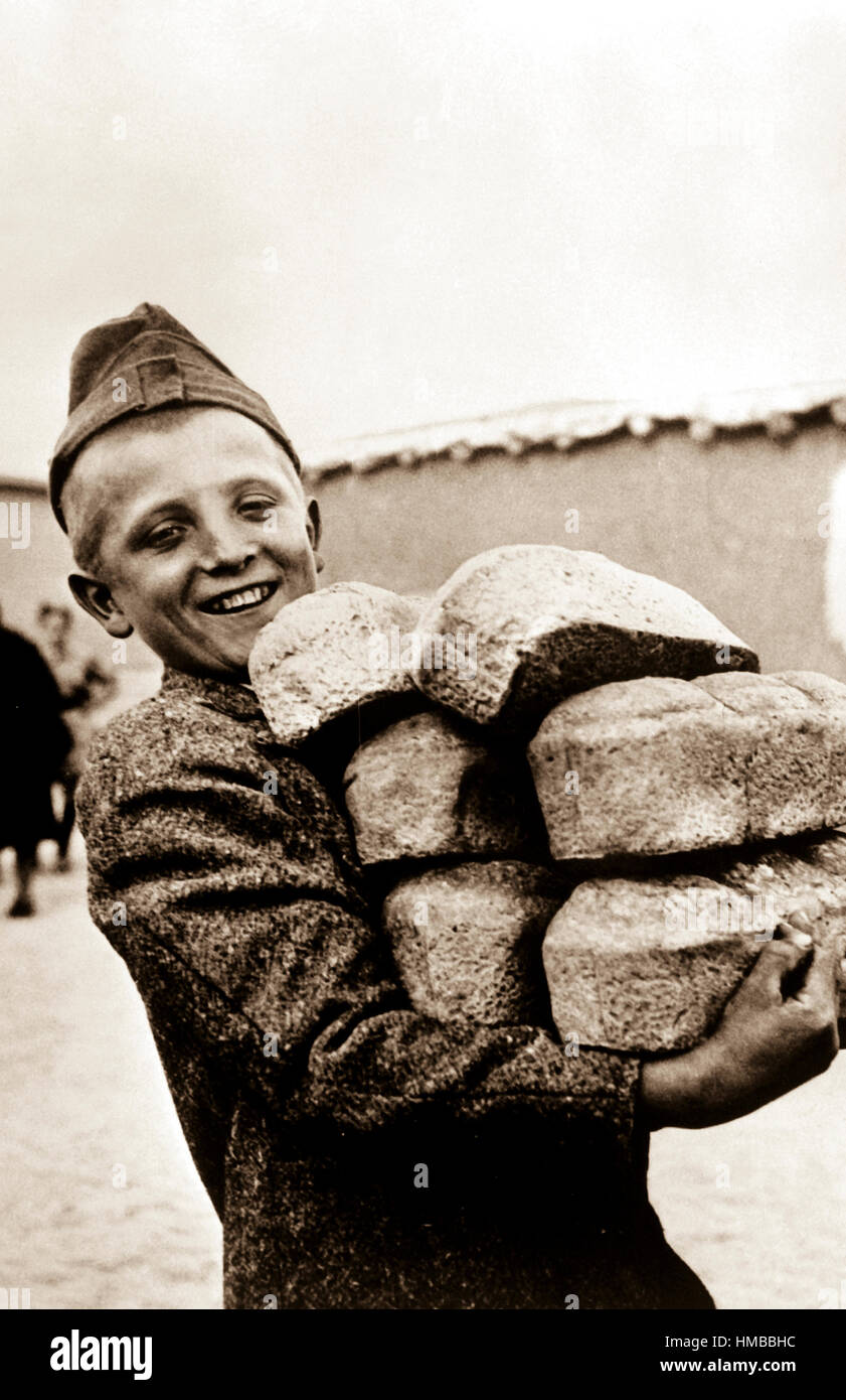 Polnische Youngster mit seinen Armen voller Brot aus Mehl geliefert durch das amerikanische Rote Kreuz.  Lächeln ist im Vorfeld genügend Brot zu essen, etwas, was er nicht bekommen würde, wenn er in seinem Heimatland Polen, Russland, ca. 1943 geblieben wäre. OWI.  (Armee) Genaues Datum erschossen unbekannte NARA Datei #: 111-SC-170234 Krieg & Konflikt buchen #: 1256 Stockfoto