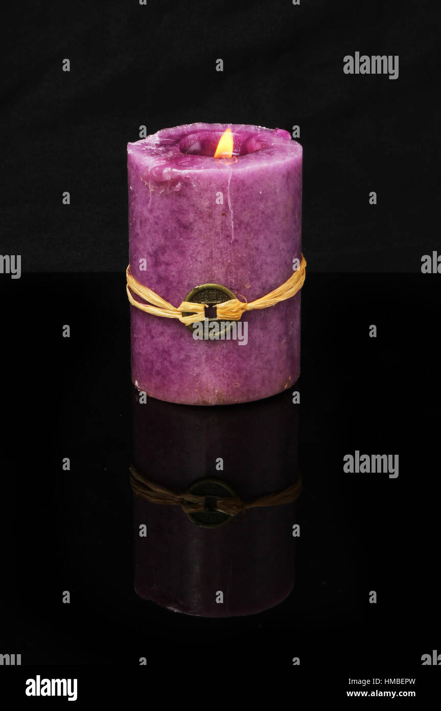 Brennende lila, Feuer, Feng Shui Kerze mit Reflexion vor einem dunklen Hintergrund Stockfoto