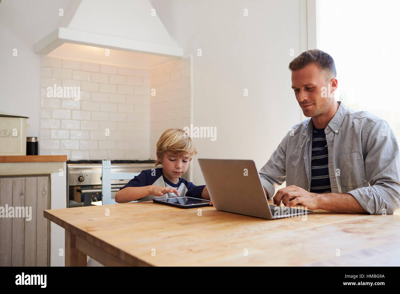 Vater und Sohn mit dem Computer am Küchentisch Stockfoto