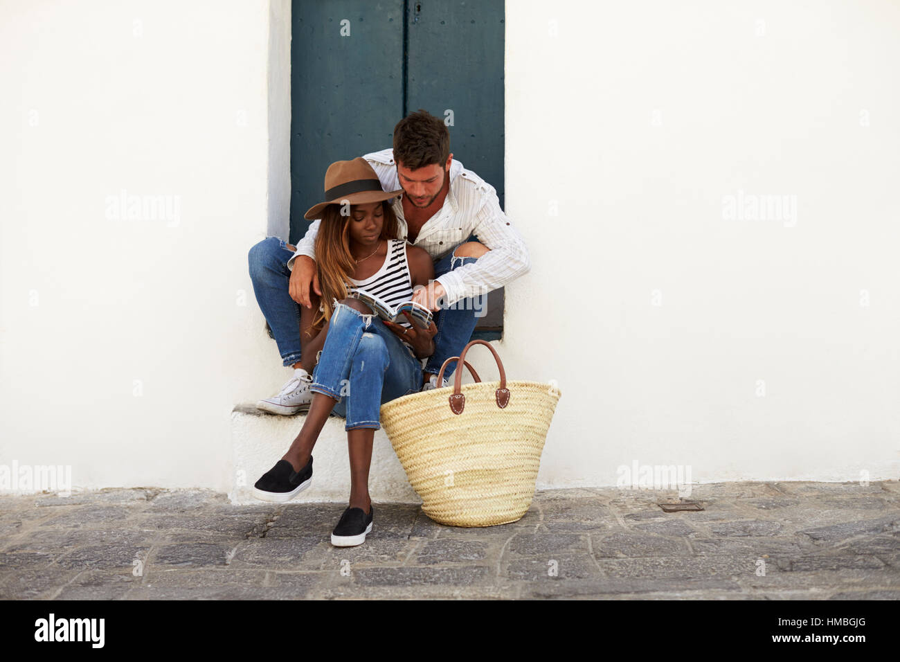 Erwachsenes paar sitzen auf Stufen betrachtet man einen Reiseführer, Ibiza Stockfoto