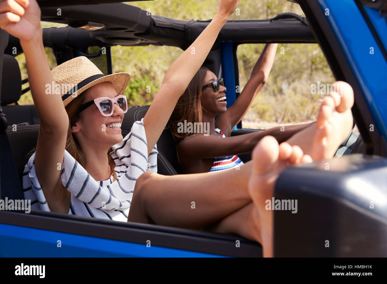 Zwei Freundinnen fahren Open Top Car auf Landstraße Stockfoto