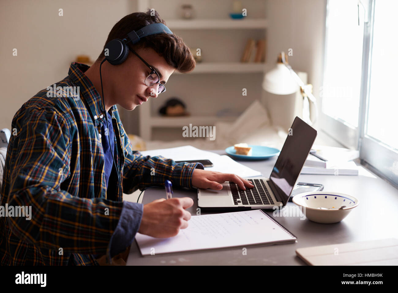 Teenager tragen von Kopfhörern arbeitet am Schreibtisch in seinem Zimmer Stockfoto