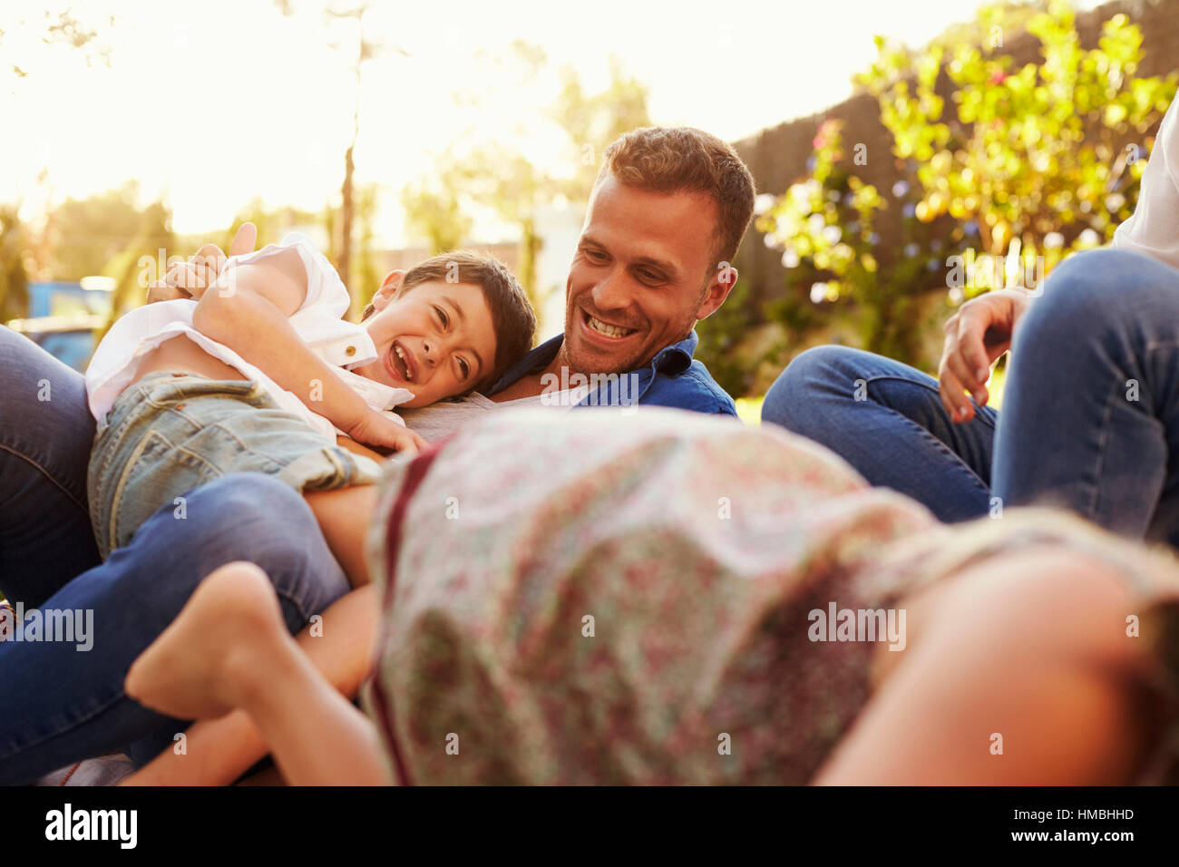 Eltern spielen mit Kindern auf Decke im Garten Stockfoto