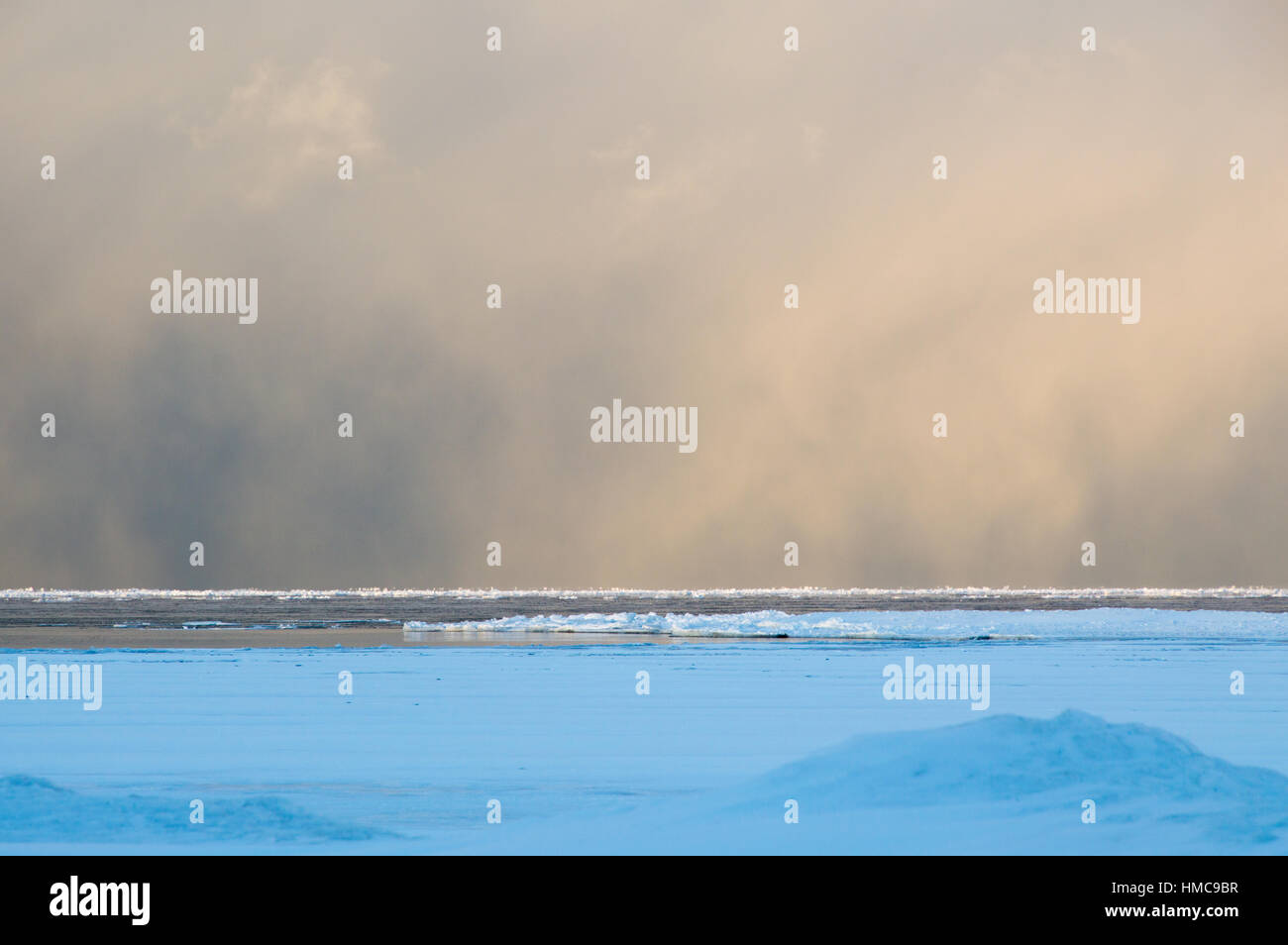 Sidelit Bö Schneewolken Rollen über die gefrorene Lake Huron bei Sonnenaufgang.  Eis schwimmt auf dem noch ruhigen Wasser. Stockfoto
