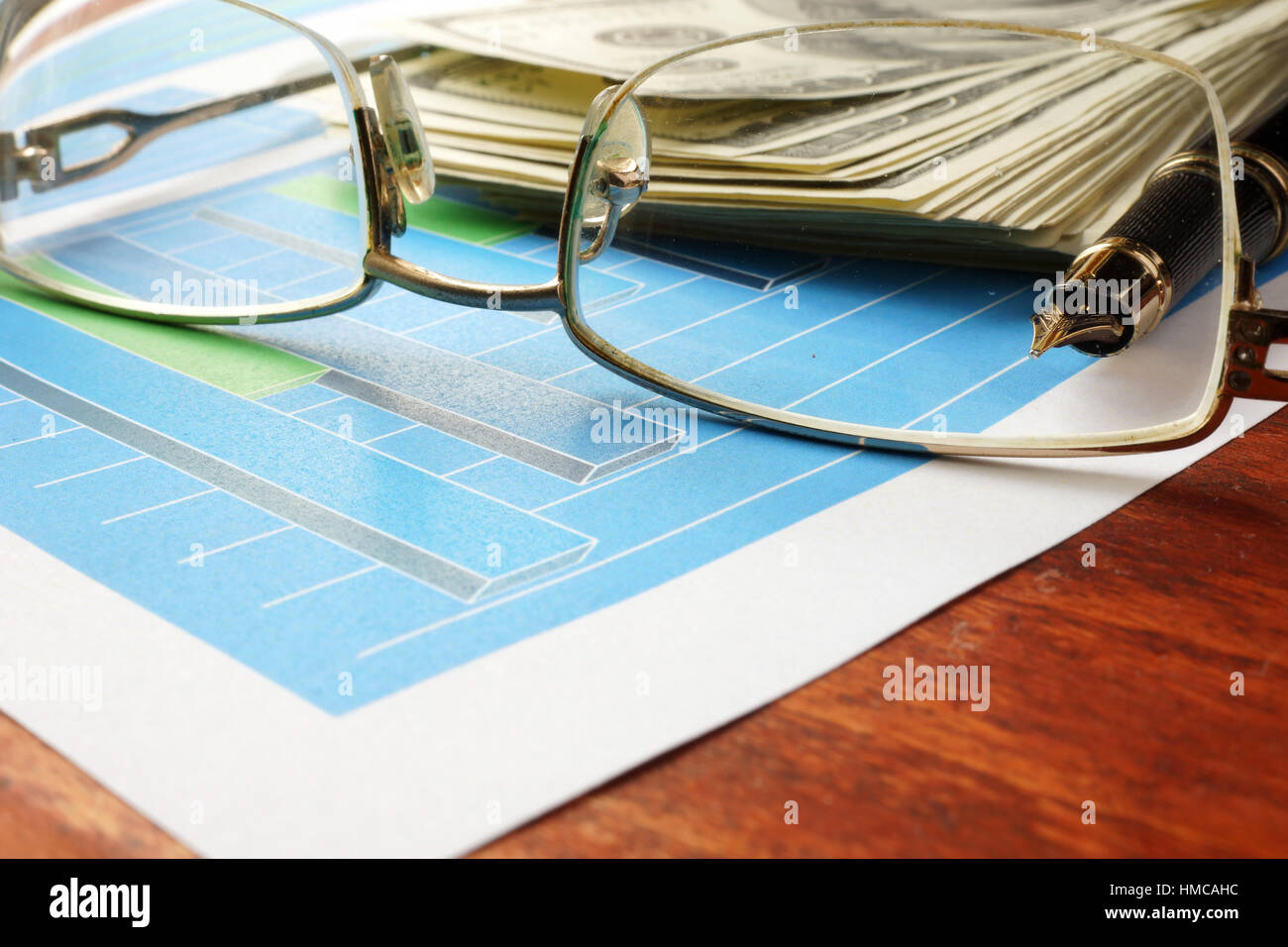 Finanzkonzept. Diagramme und Gläser auf einer Holzfläche. Stockfoto