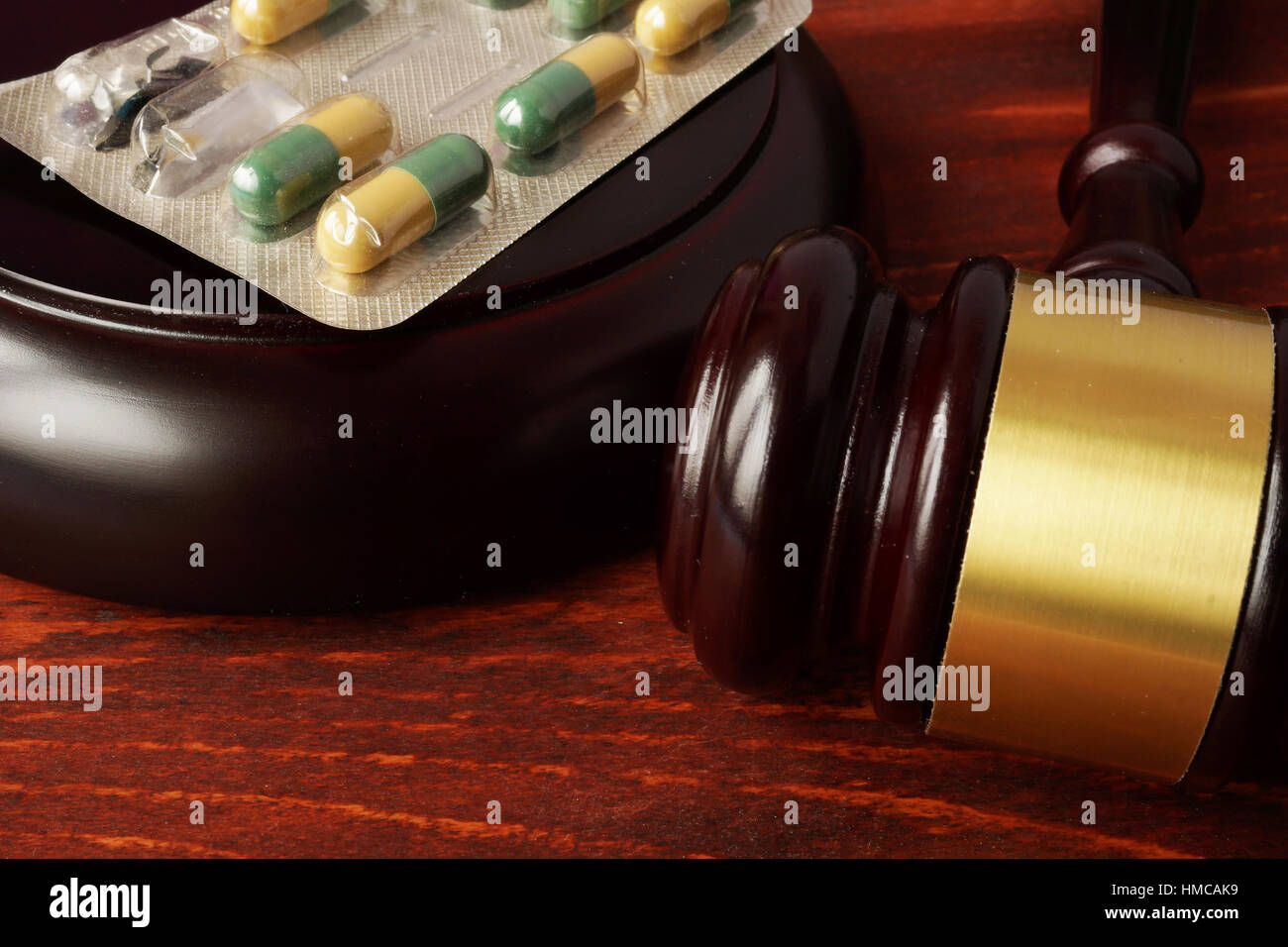 Hammer und Pillen auf einem Holztisch. Medizinische Verbrechen. Stockfoto