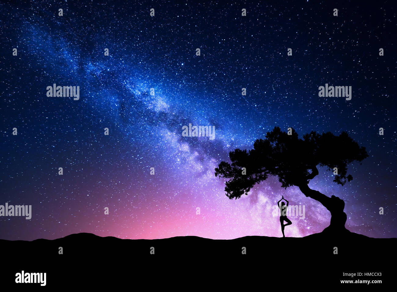 Milky Way mit alten Baum und Silhouette einer stehenden Frau Yoga zu praktizieren. Landschaft mit Meditierenden Mädchen unter dem Baum Stockfoto