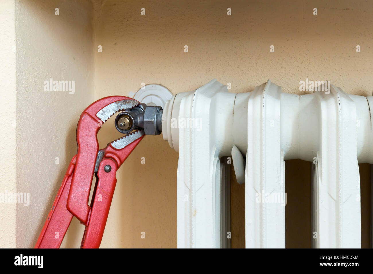 Klempner am Arbeitsplatz installieren ein thermostatisches Ventil auf einem Heizkörper Stockfoto