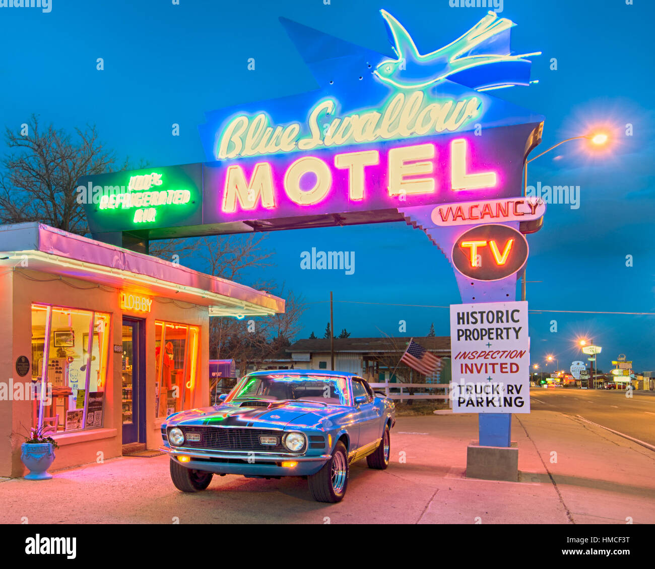 Dämmerung im historischen blauen schlucken Motel an der Route 66. 1970 Ford Mustang Oldtimer ist unter den ikonischen Leuchtreklame geparkt. Stockfoto