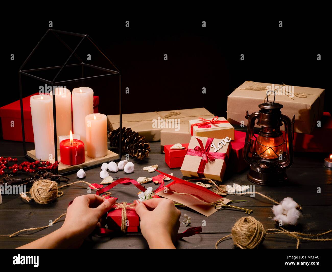 Close-up Teilansicht des weiblichen Händen Verpacken Geschenk am Holztisch mit Geschenken und Dekorationen Stockfoto