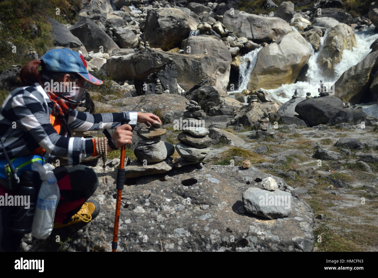Young South East Asian Frau Gebäude Stein Cairns im Flusstal Modi Khola im Annapurna Sanctuary, Himalaya, Nepal, Asien. Stockfoto