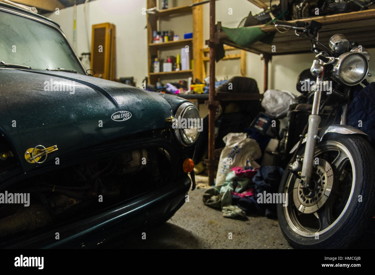 Klassischen Austin Mini Cooper und Kawasaki Motorrad in der heimischen Garage/Werkstatt. Stockfoto