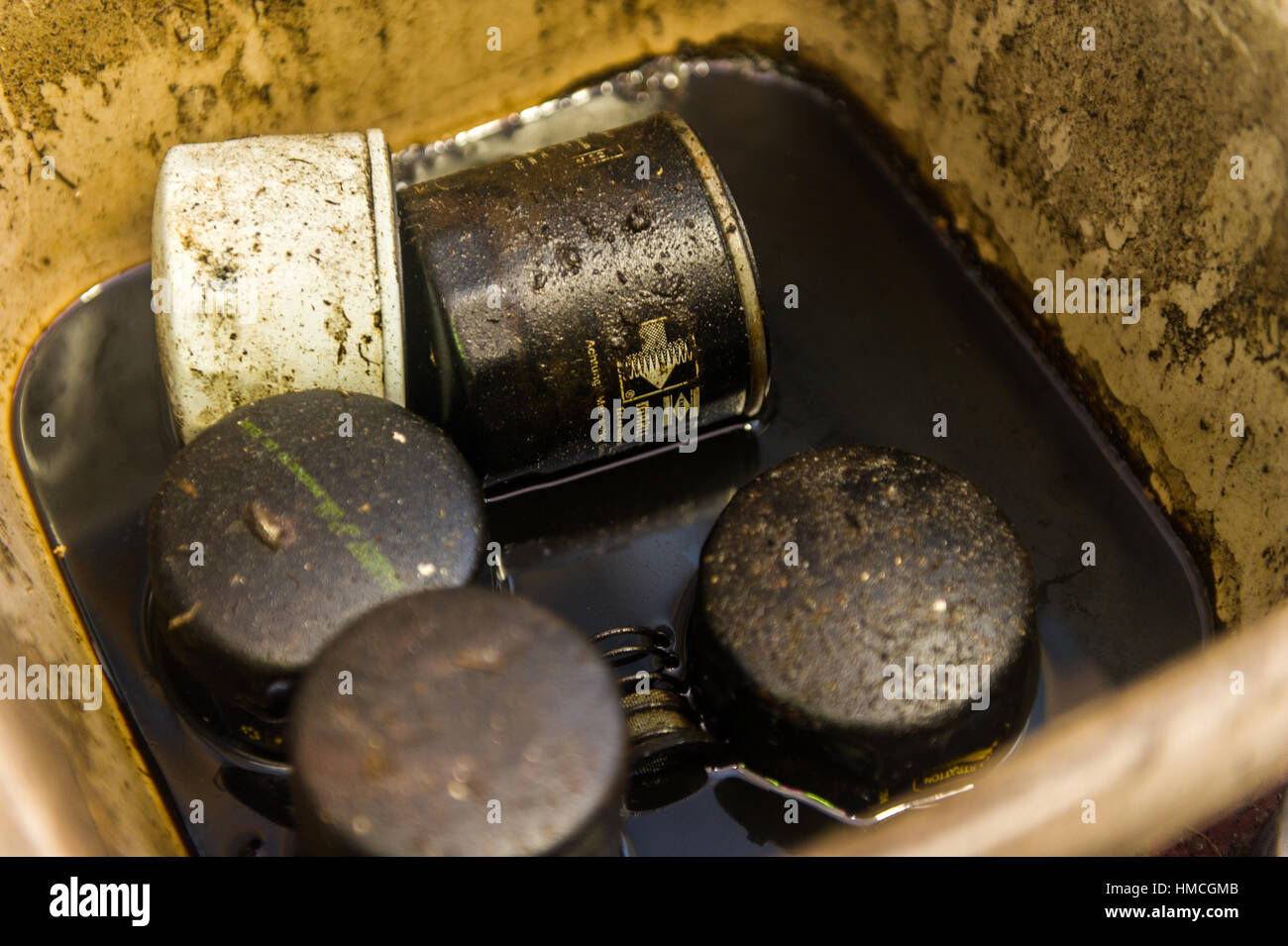 Alt und Gebrauchtwagen Ölfilter in einer Schüssel voller Öl verschmutzt/verwendet. Stockfoto