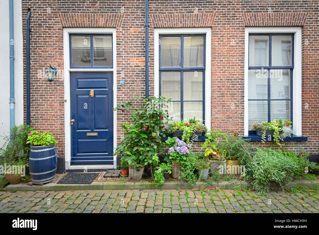 Fassade des alten holländischen Ziegelhaus mit Blumen in Töpfen Stockfoto