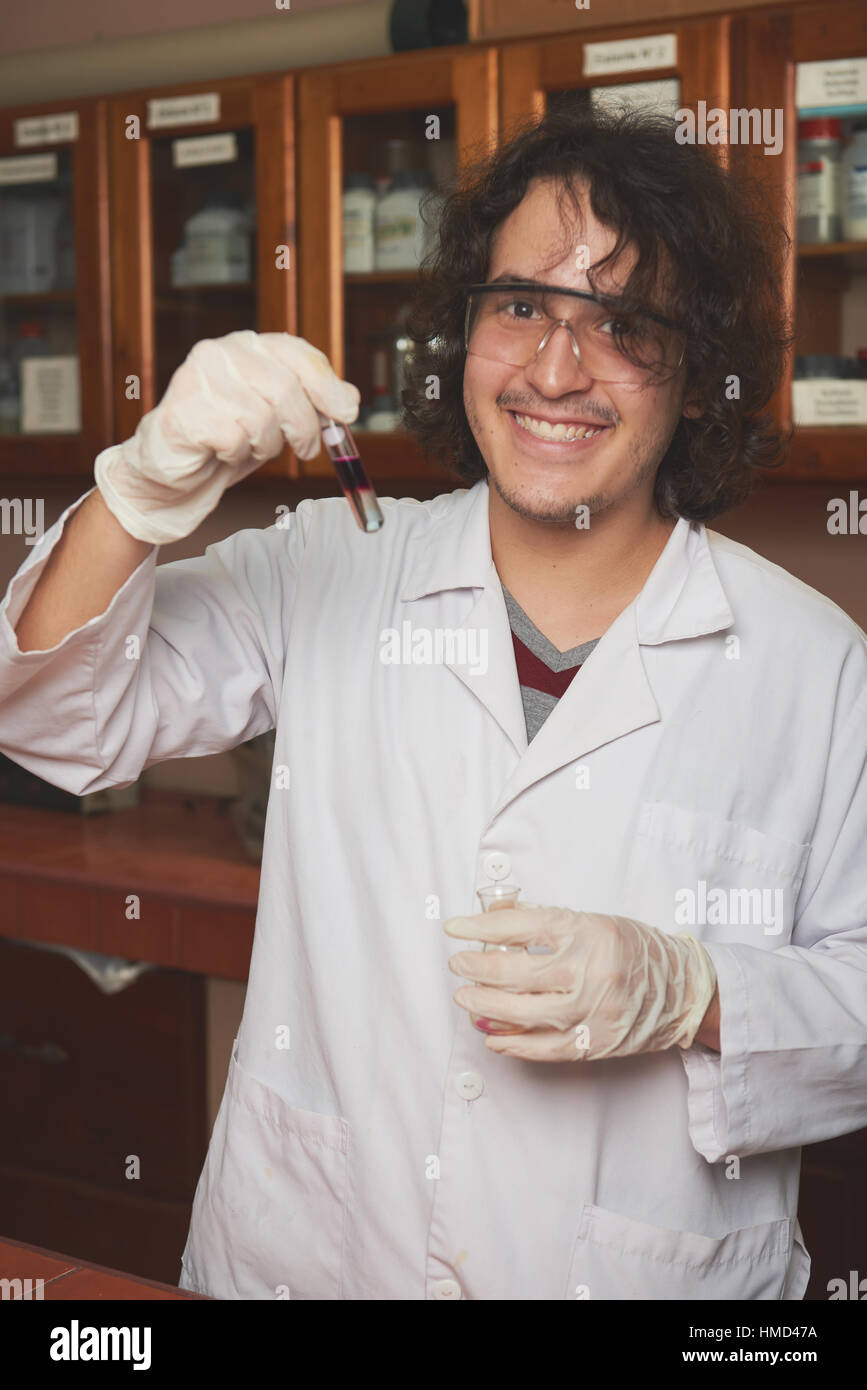 junge Wissenschaftler lächelnd mit Chemikalien im Labor Stockfoto