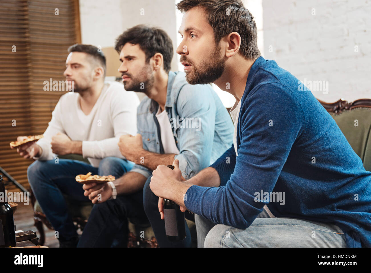 Ernste konzentrierte Männer beobachten eines Fußballspiels Stockfoto