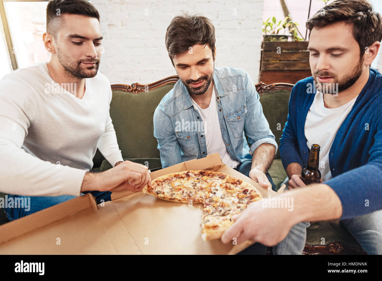 Attraktive junge Männer, die die Scheiben von pizza Stockfoto