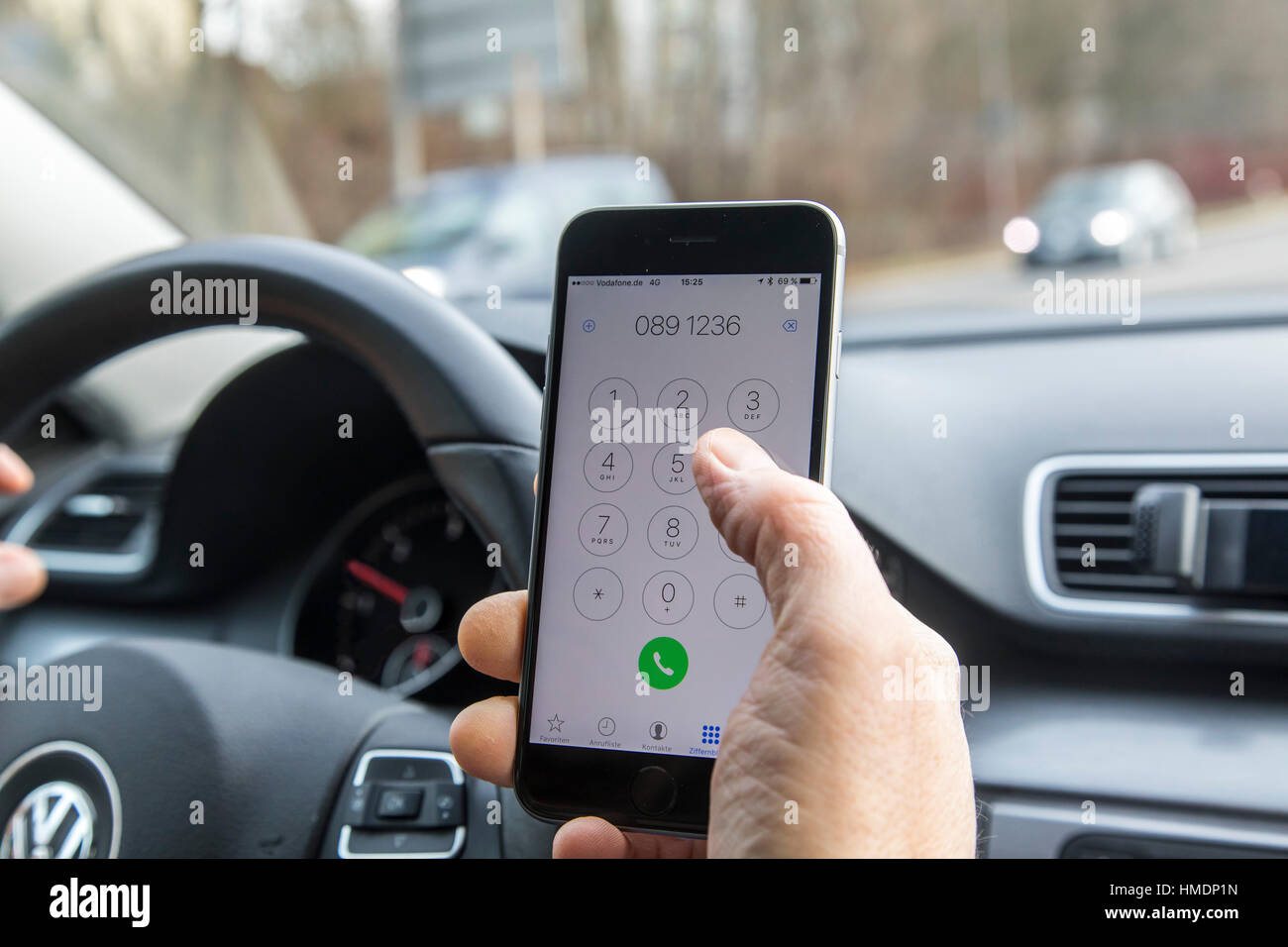 Ein Autofahrer ist ein Handy, Smartphone, mit, während der Fahrt des Autos, Stockfoto