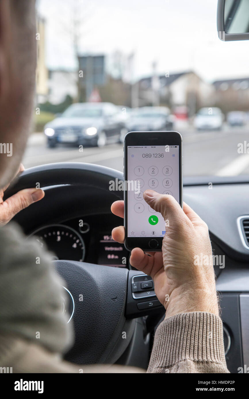 Ein Autofahrer nutzt ein Handy, Smartphone, während der Fahrt des Autos wählen, Stockfoto