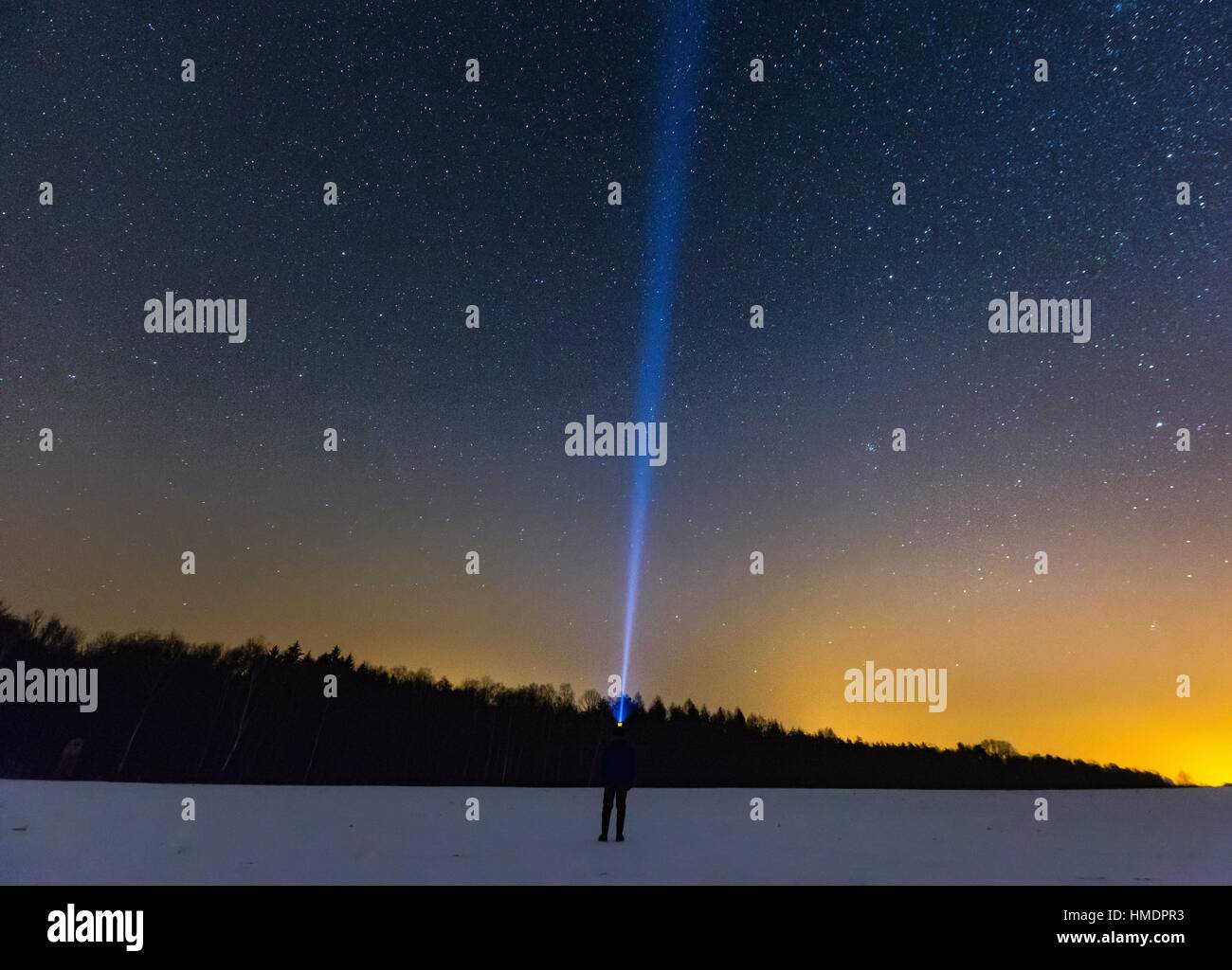 Mann mit Kopf Taschenlampe zeigt Licht am Sternenhimmel. Nachtlandschaft Stockfoto