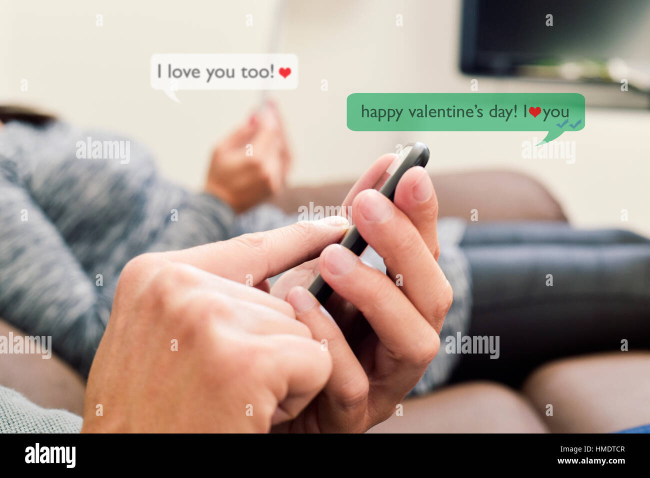 ein junger kaukasischen Mann und eine junge kaukasischen Frau senden und empfangen von SMS-Nachrichten in ihren Smartphones mit dem Text Happy Valentines Day, ich liebe Stockfoto