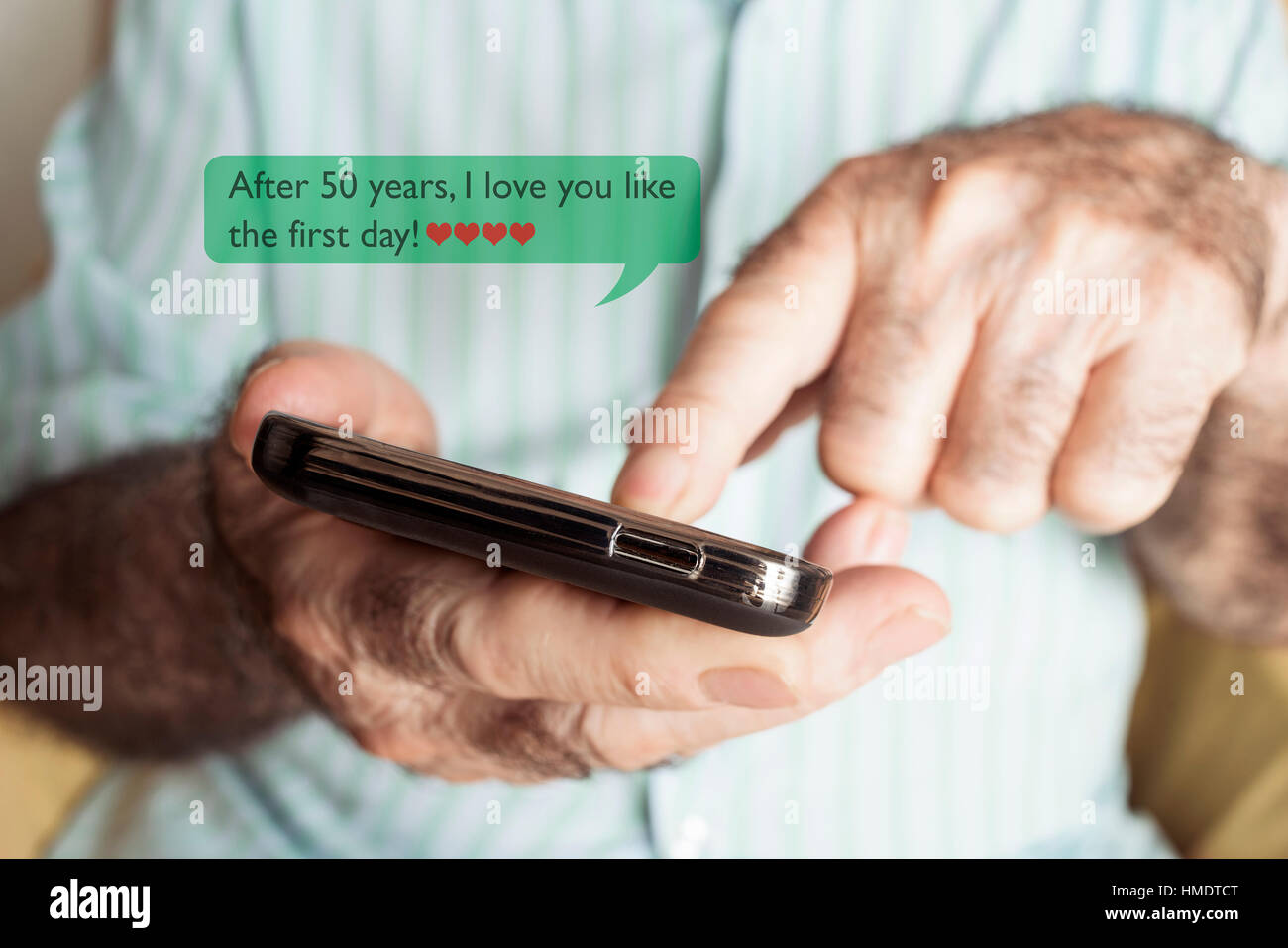 Nahaufnahme von einem alten kaukasischen Mann senden oder eine SMS-Nachricht in sein Smartphone mit dem Text zu lesen, nach 50 Jahren ich dich wie am ersten Tag Liebe Stockfoto