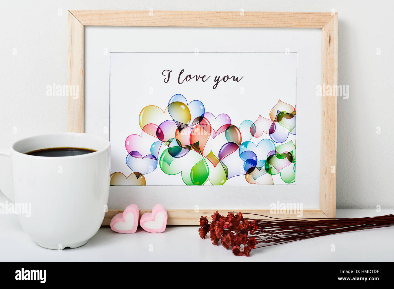 ein Holz-gerahmte Bild mit einer Illustration von mir, mit einige Herzen und den Text ich liebe dich, eine Tasse Kaffee, einige herzförmige Marshmallow gemacht Stockfoto