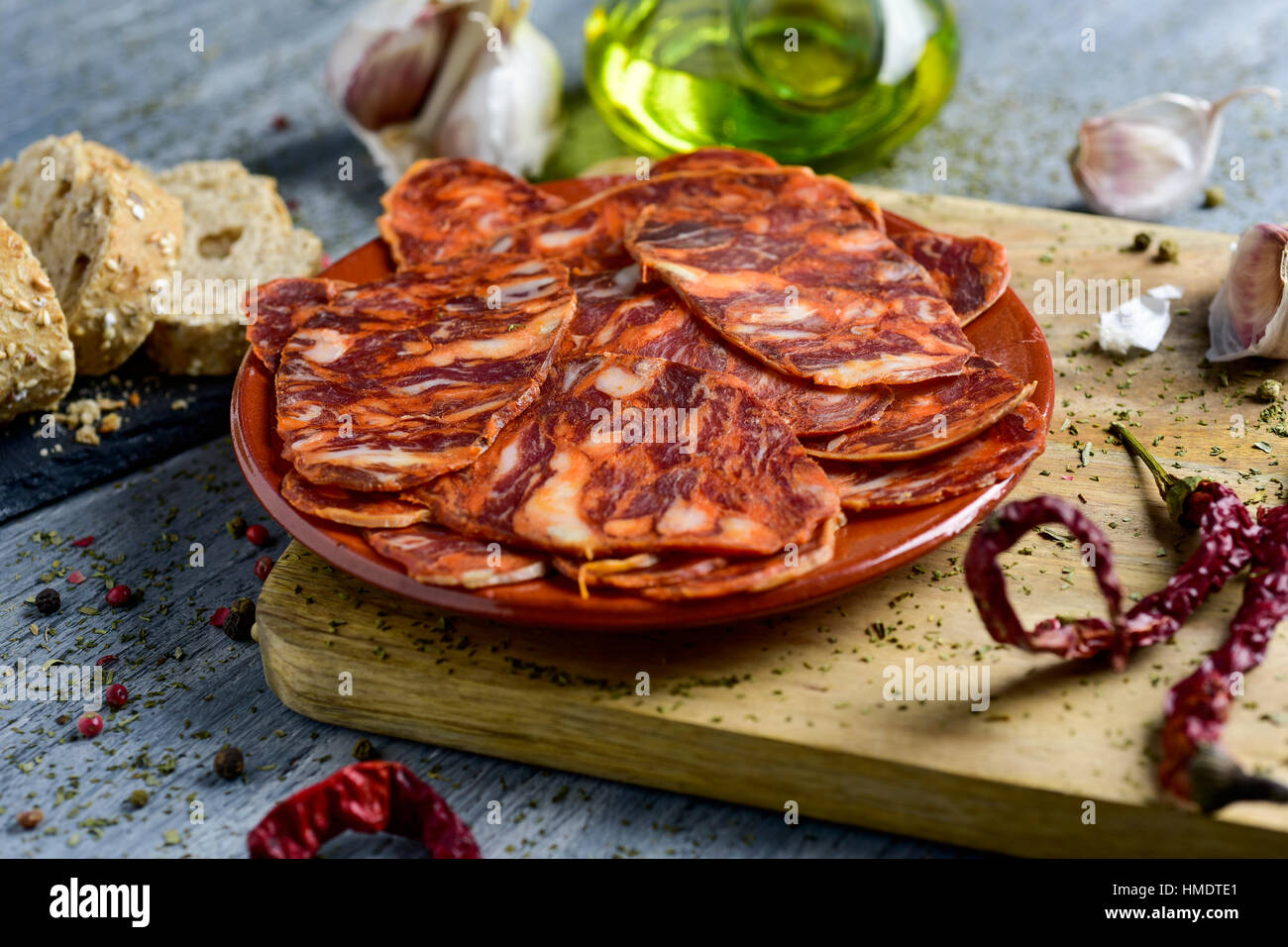 Nahaufnahme eines Steingut Platte mit einigen Scheiben von spanischen Chorizo, Wurstwaren Wurst, einige Scheiben Brot, ein Glas Menage mit Olivenöl und einige g Stockfoto