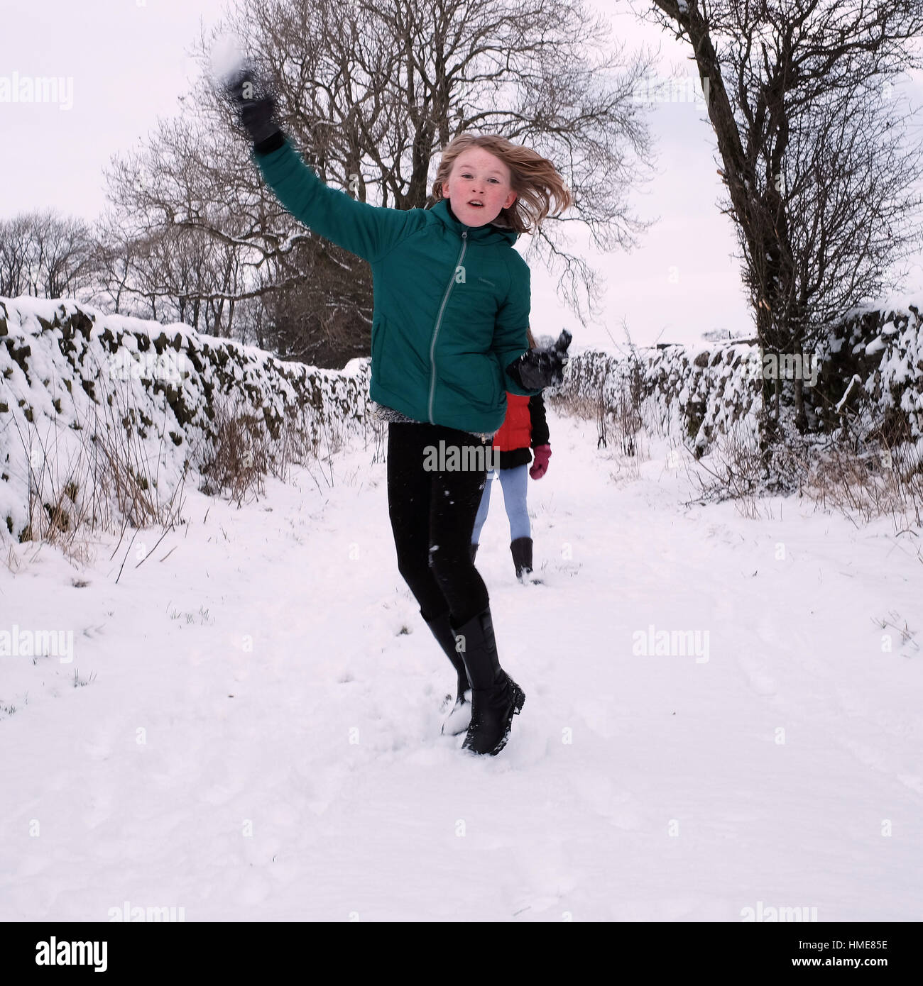 Eine Mädchen wirft einen Schneeball im Freien an einem verschneiten Wintertag Stockfoto