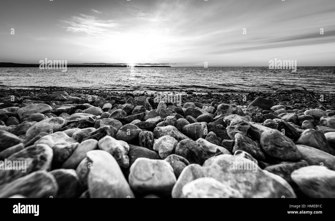 Steinen am Strand bei Sonnenuntergang auf dem Meer. Landschaftsfoto von Sonnenaufgang oder Sonnenuntergang am Naturstrand in Piran, Slowenien. Stockfoto
