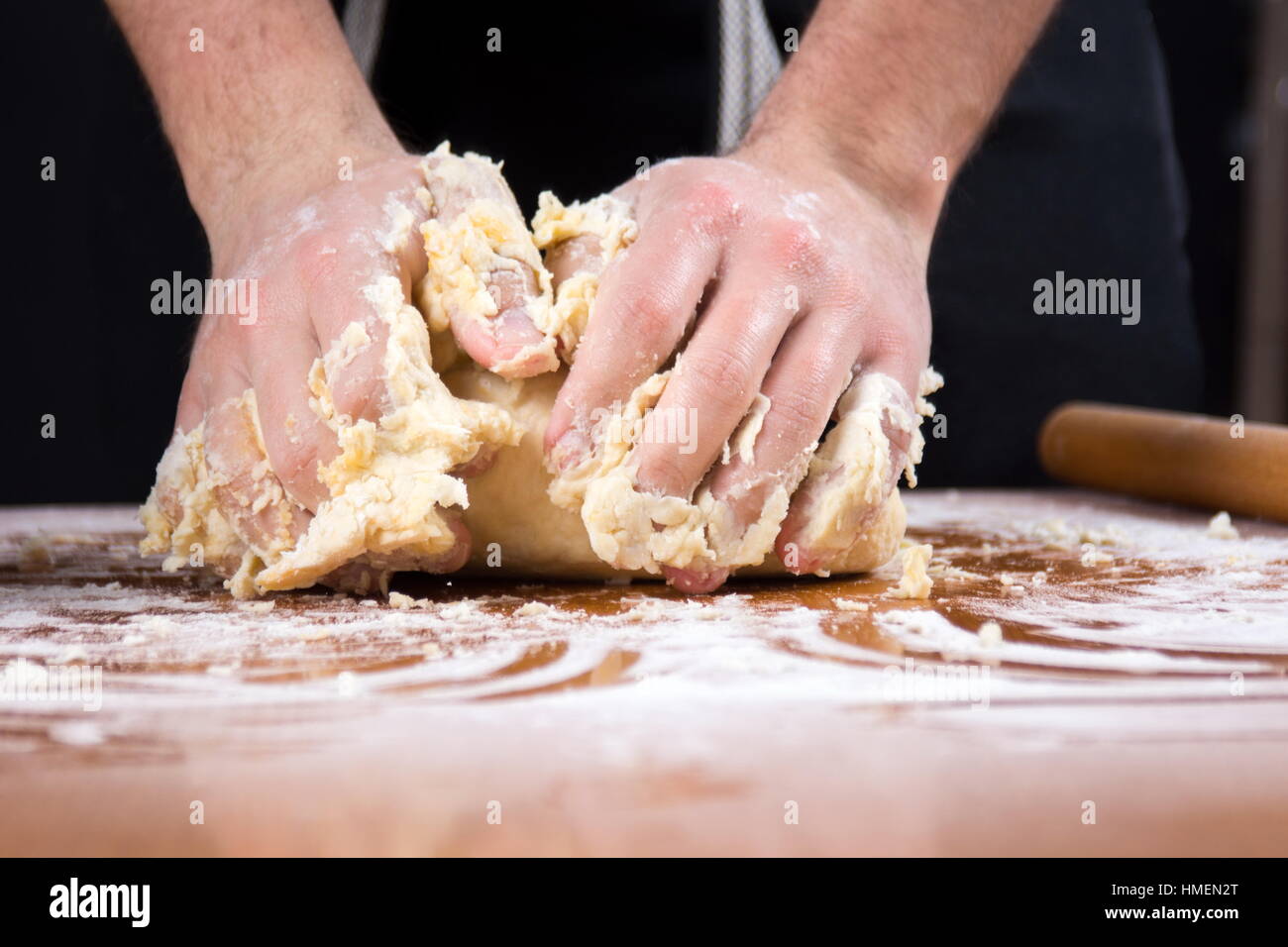 Männliche Bäcker kneten Teig auf Mehl bedeckt Tabelle Stockfoto