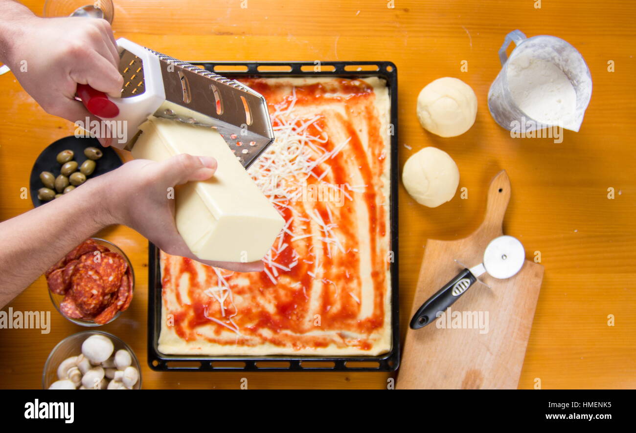 Mann reiben Käse auf einem Pizzateig. Pizza backen Stockfoto