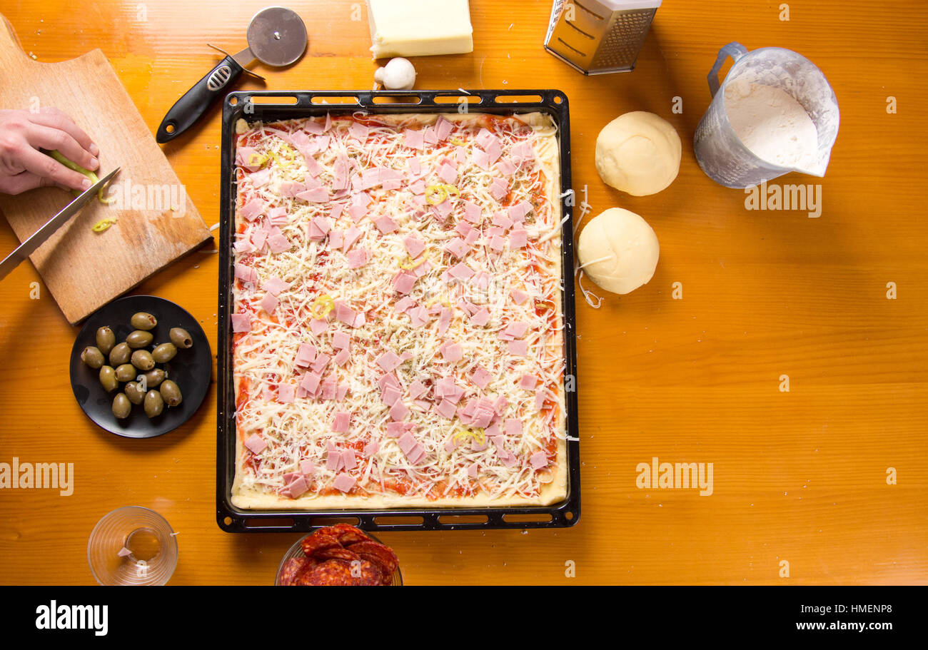 Männlichen Chef Pizza auf einer Pfanne Zutaten hinzufügen Stockfoto