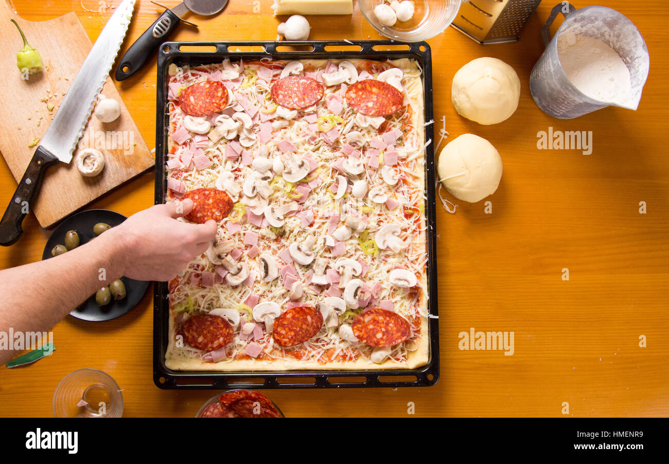 Männlichen Chef Pizza auf einer Pfanne Zutaten hinzufügen Stockfoto