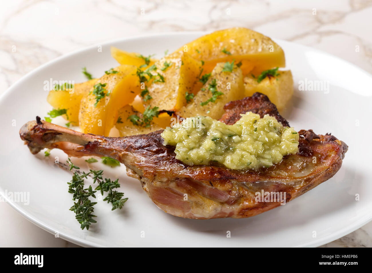 Gebratene Ente mit goldenen Kartoffeln und Knoblauch-Sauce mit Kräutern auf Platte Stockfoto