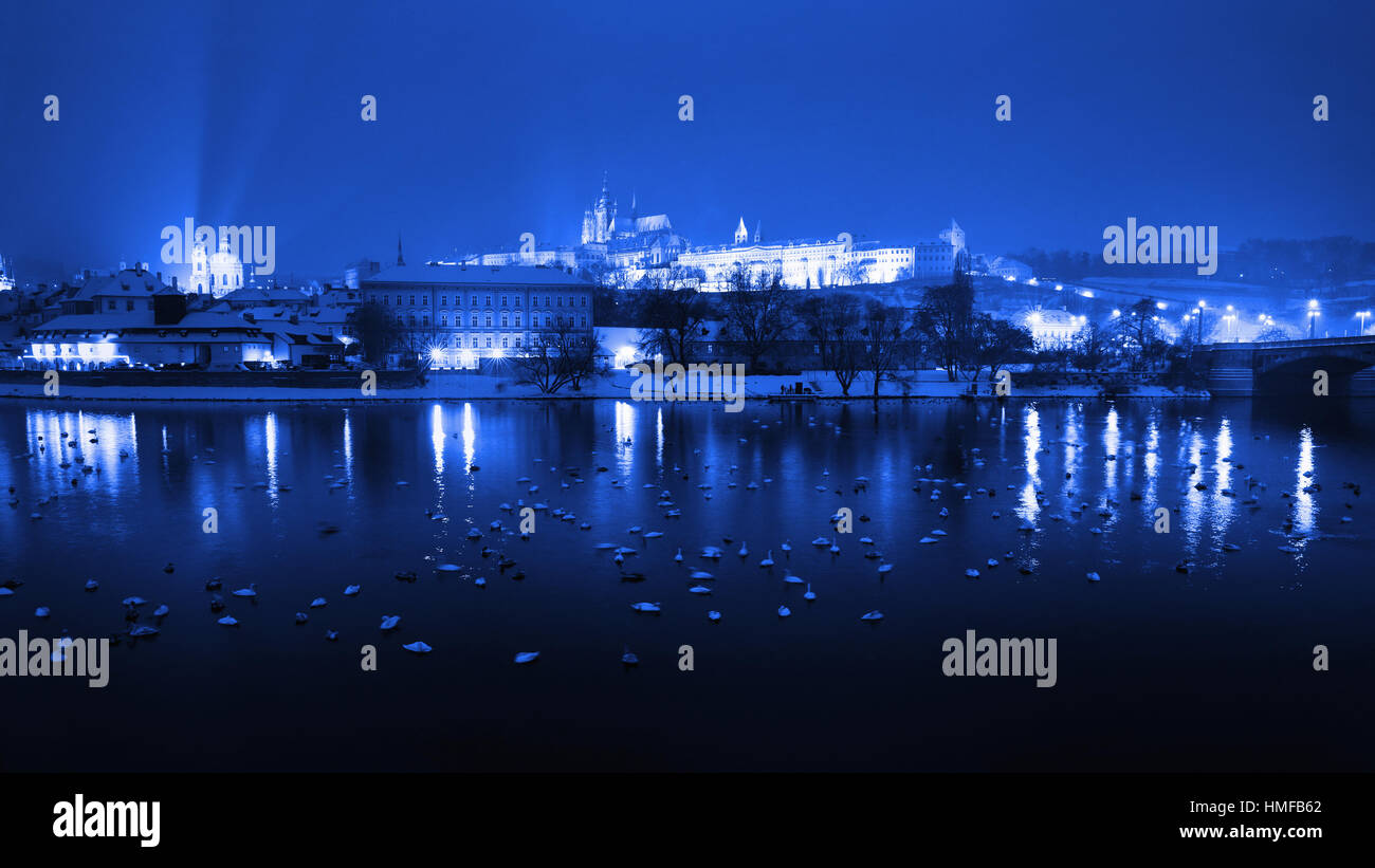 Nacht-Winter-Prag, das Schloss und St.-Veits-Dom. Verschneite Dächer der Altstadt, im Hintergrund Prager Burg. Tschechische Republik. Schwäne auf dem Ri Stockfoto