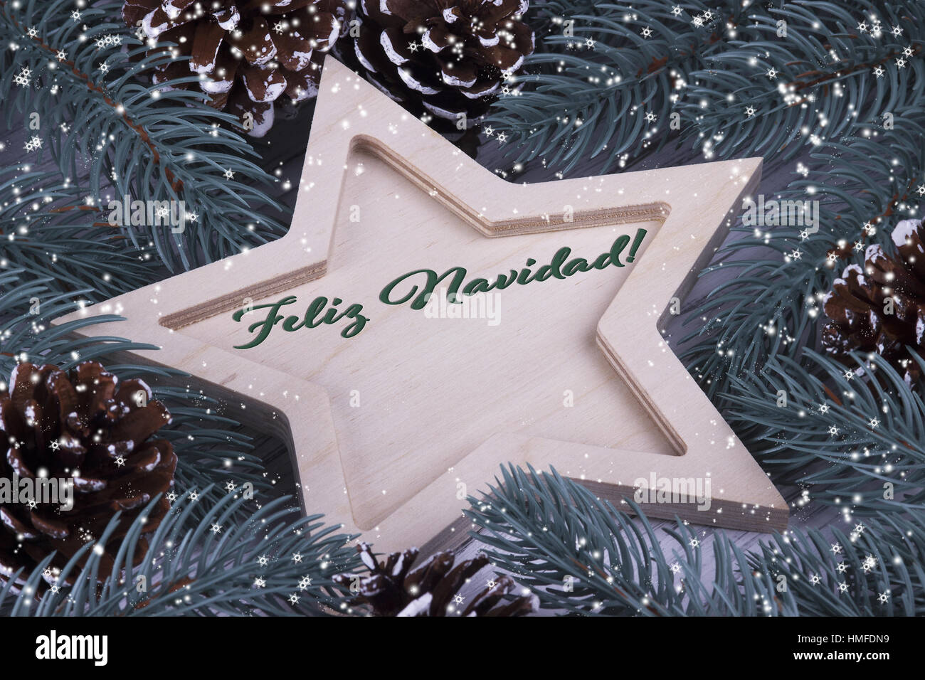 Weihnachten Weihnachtsurlaub Silvester Grusskarte mit hölzernen fünf Spitzen Sterne Tannenzapfen Zweige und Text Feliz Navidad Stockfoto