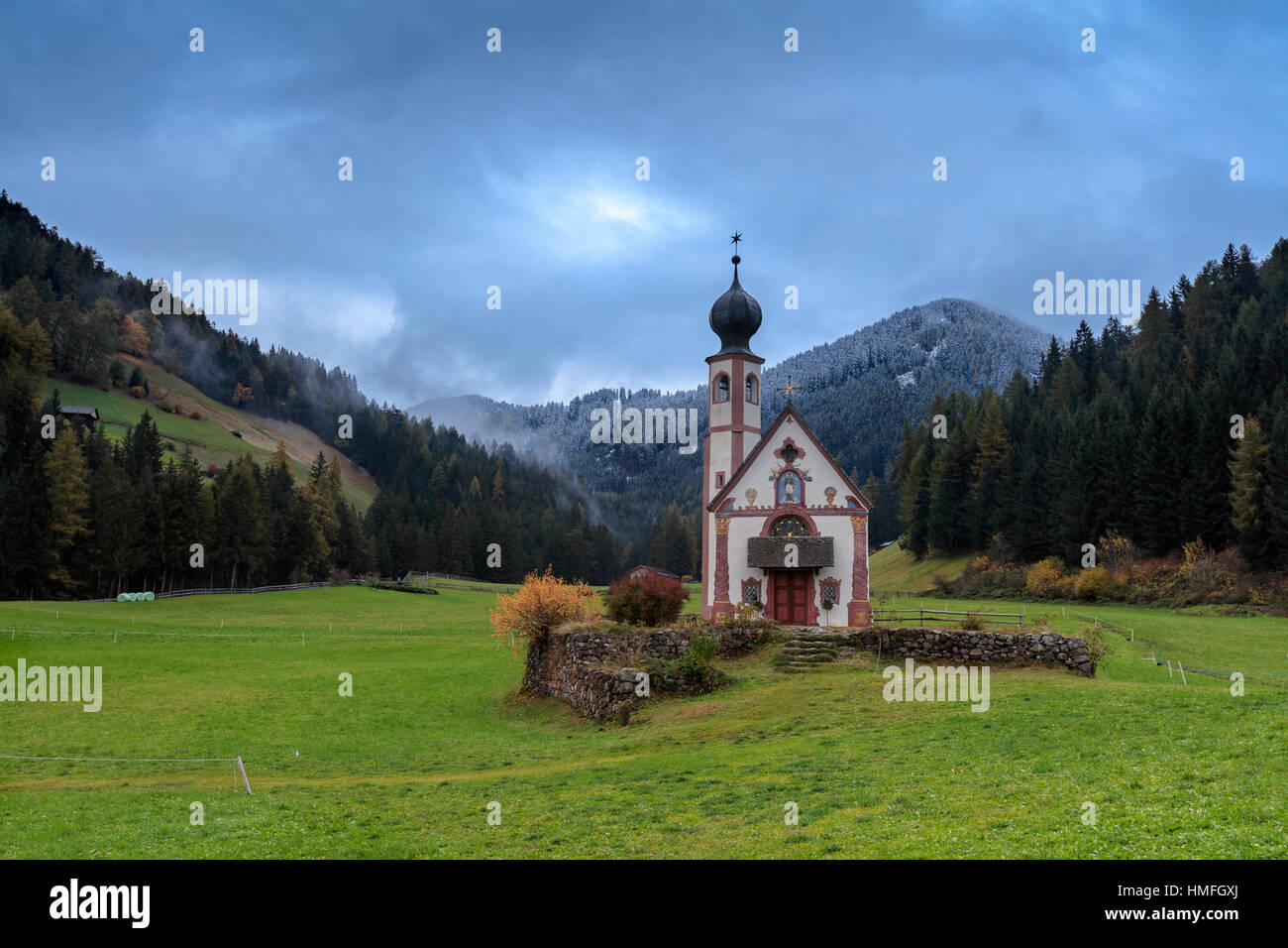 Wolken auf Kirche von Ranui, umgeben von Wiesen und Wäldern im Herbst, St.Magdalena, Villnösser Tal, Südtirol, Dolomiten, Italien Stockfoto
